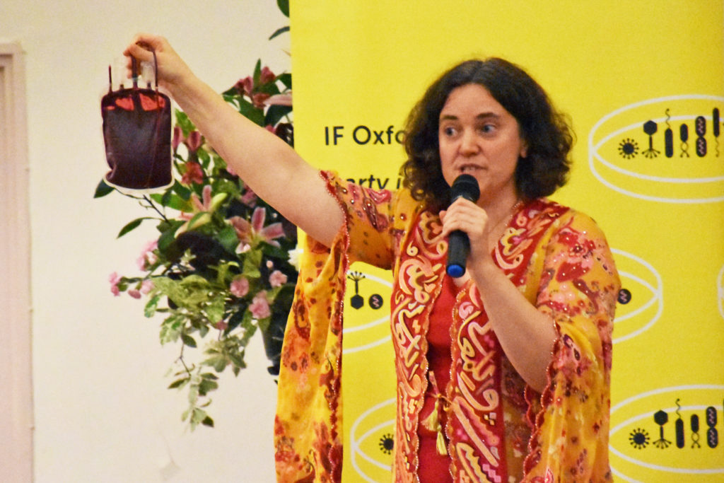 Noemi Roy at the 'Battle for the Iron Crown' event, holding a bag of blood.