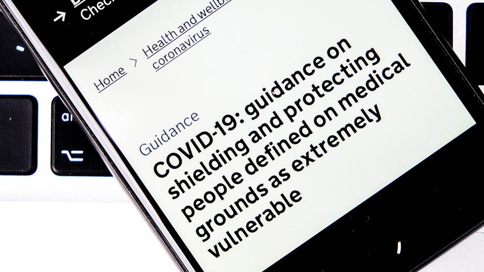 Mobile phone showing government guidance on shielding and protecting vulnerable people  - this guidance was based on the QCovid tool.