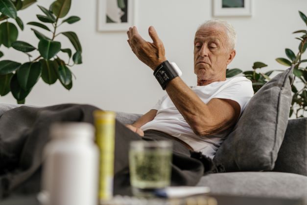 Older man at home checks a wearable monitor 