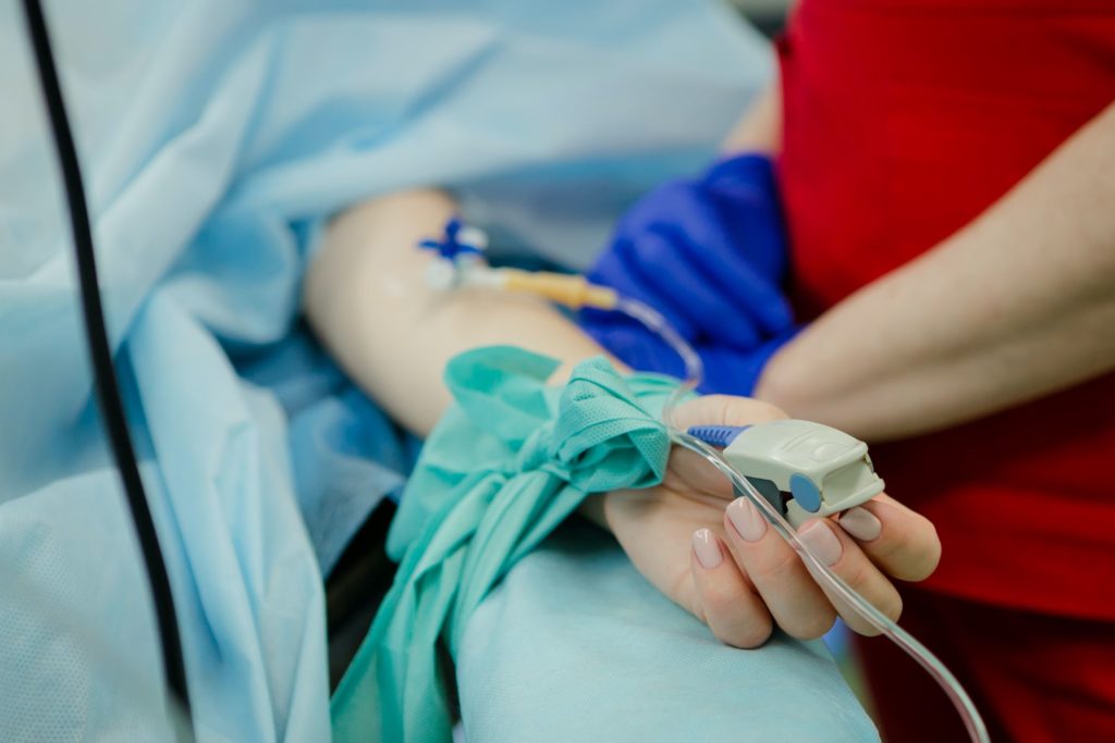 Hands of clinician and patient being treated in intensive care
