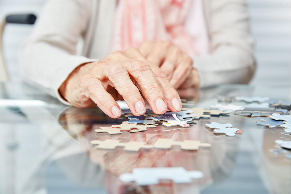 Hands of an elderly woman doing a jigsaw puzzle