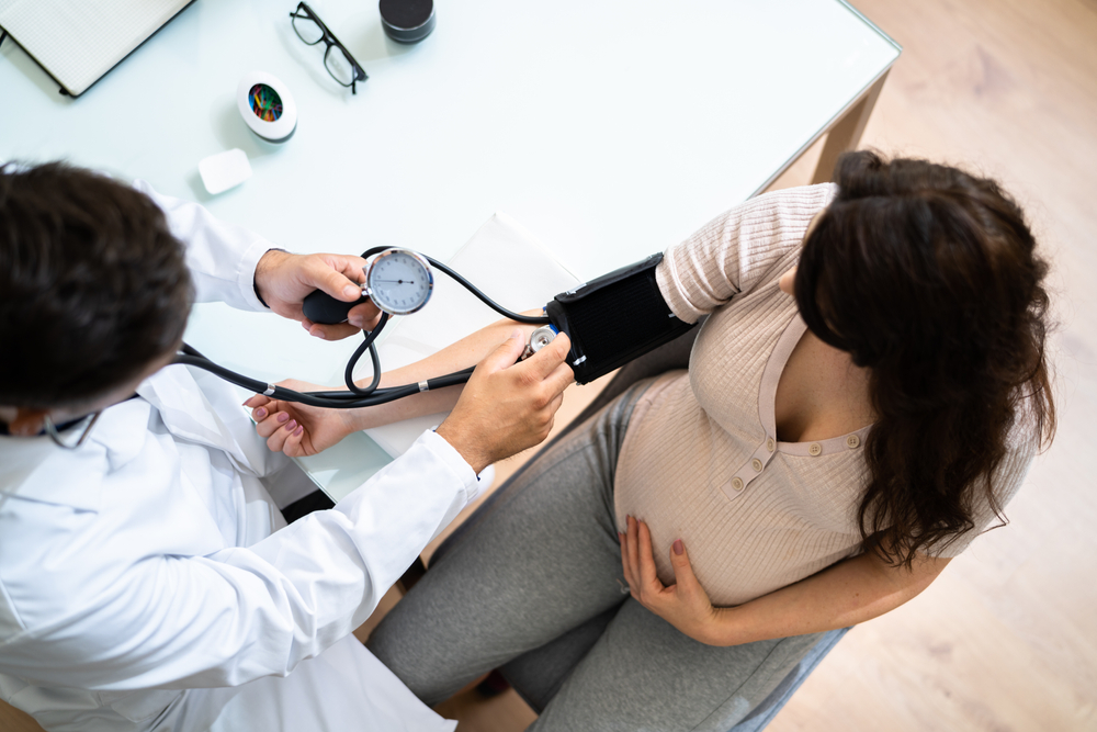 Male doctor measuring blood pressure of pregnant woman