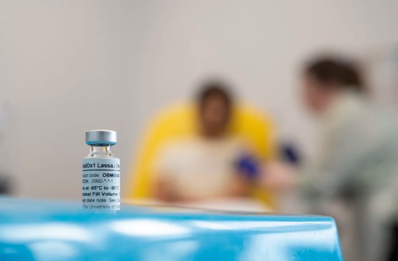 vial of Lass fever vaccine, with out-of-focus nurse and patient in the background