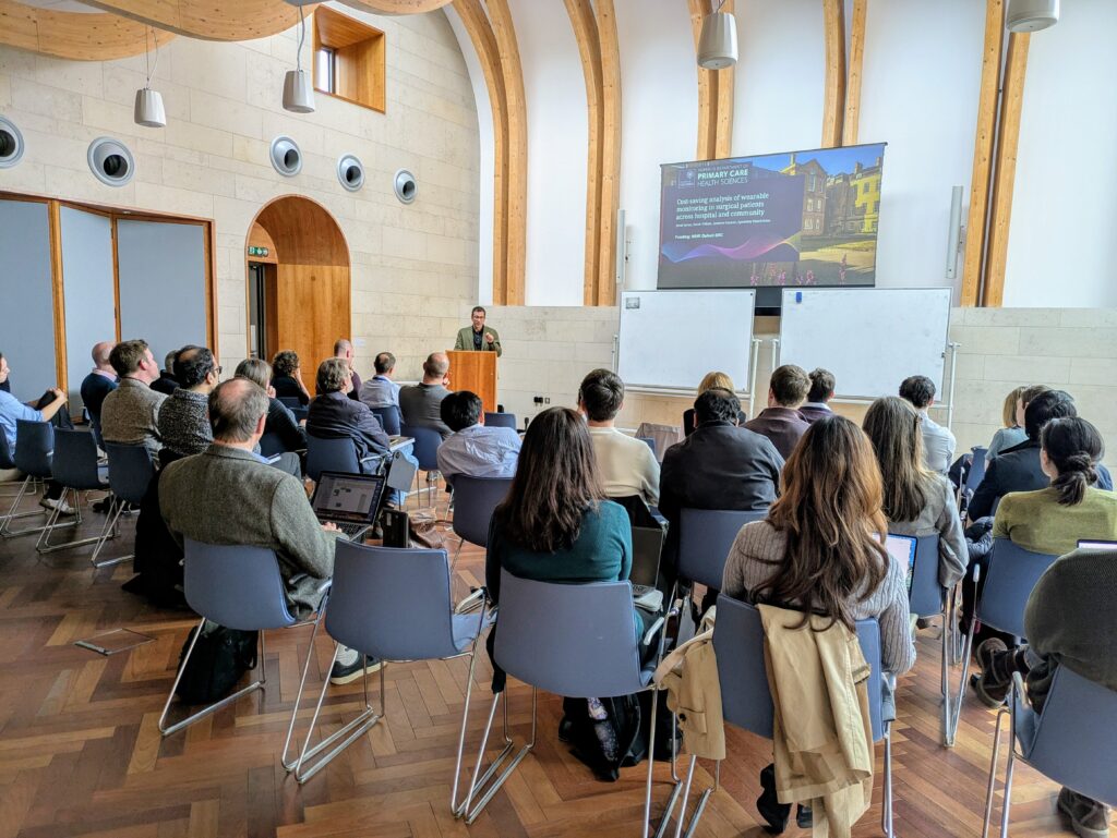 room of people listening to a presenter speaking at a lectern 