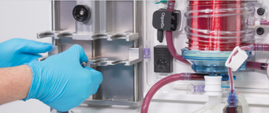 close-up of gloved hands working with an organ perfusion machine 