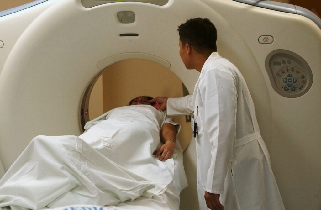 A radiographer helps a patient into a cardiac MRI machine 