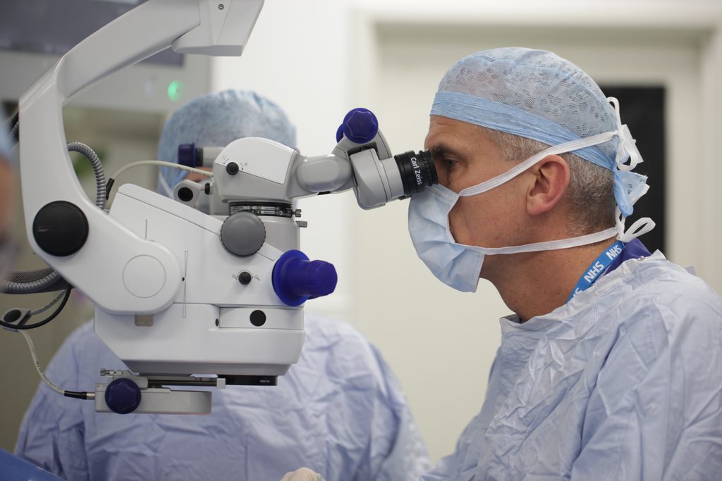 A surgeon (Professor MacLaren) looking through a microscope while conducting eye surgery 
