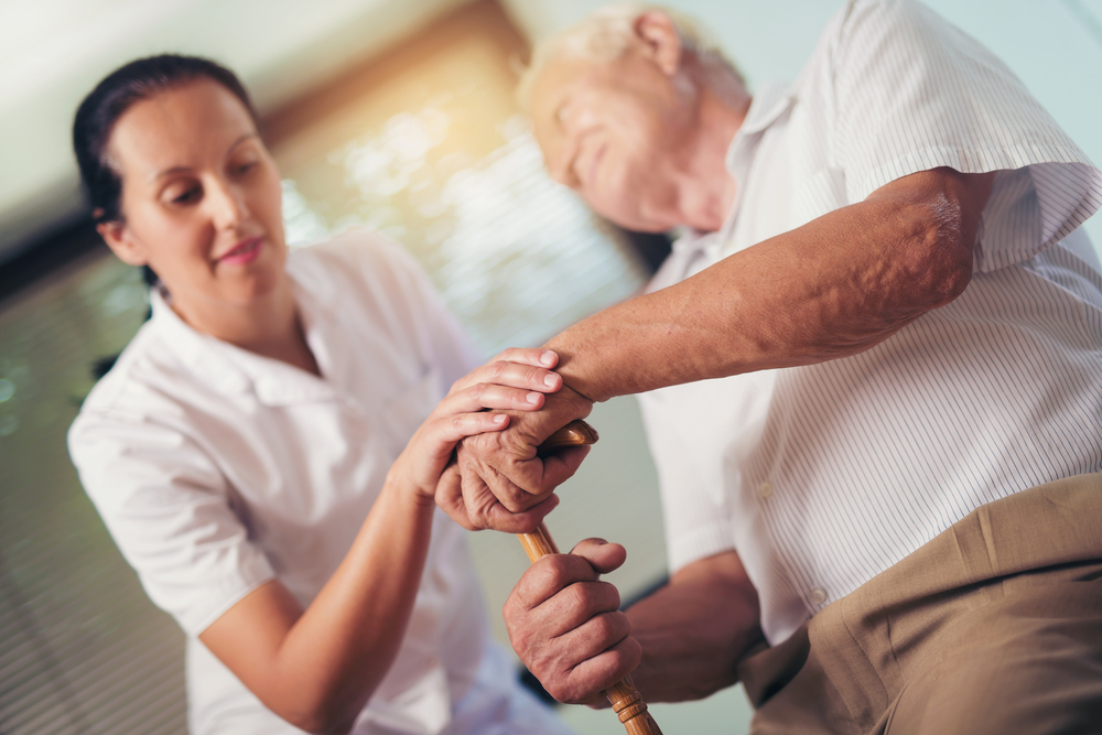 Young woman holding hand of older man with walking stick